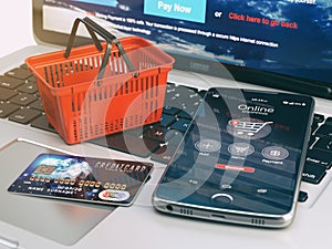 Mobile phone, shopping basket and credit card on laptop keyboard