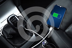 Mobile phone ,smartphone, cellphone is charged ,charge battery with usb charger in the inside of car. modern black car interior