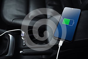 Mobile phone ,smartphone, cellphone is charged ,charge battery with usb charger in the inside of car. modern black car interior