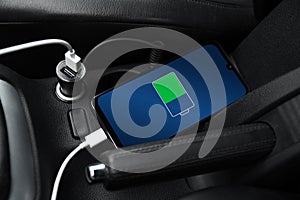 Mobile phone ,smartphone, cellphone is charged ,charge battery with usb charger in the inside of car. modern black car interior