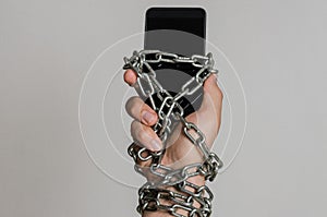 Mobile phone smartphone chained to hands with chains on a light background