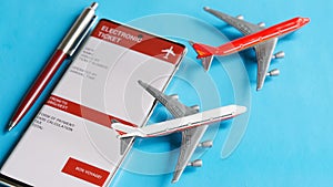 Mobile phone - smartphone with an electronic air ticket form next to toy passenger planes and a fountain pen. Concept of buying