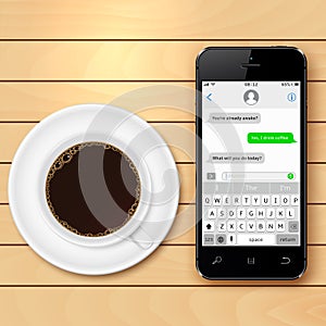 Mobile phone with sms chat on screen and coffee cup on wooden table