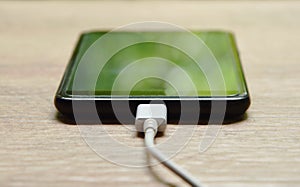 Mobile phone stabbing in rechargeable battery with white rubble cable on table background