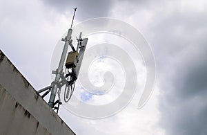 Mobile phone transmitter antenna on sky with many clouds