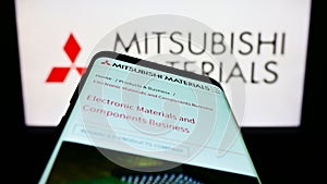 Mobile phone with webpage of company Mitsubishi Materials Corporation (MMC) on screen in front of logo.