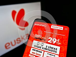 Mobile phone with webpage of Spanish telecommunications company Euskaltel S.A. on screen in front of business logo.