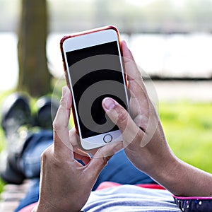 Mobile phone in woman`s hand in a deckchair against the background of the river. Telephone, Deckchair, green grass, river. Time t