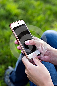 Mobile phone in woman's hand in a deckchair against the background of the river. Telephone, Deckchair, green grass, river. Time t