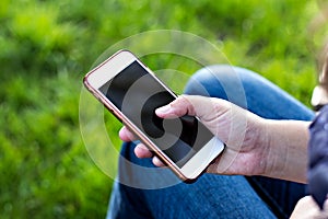 Mobile phone in woman's hand in a deckchair against the background of the river. Telephone, Deckchair, green grass, river. Time t