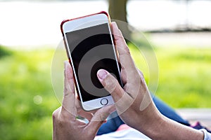 Mobile phone in woman's hand in a deckchair against the background of the river. Telephone, Deckchair, green grass, river. Time t