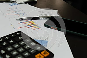 Mobile Phones business documents graphs and chart accounting finance  marketing and reports and pen on desk