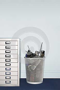 Mobile phones in trash can by filing cabinet