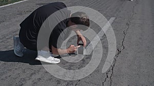 Mobile photo concept. Young man taking photos on mobile phone of his girlfriend having fun at the an empty road