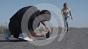 Mobile photo concept. Young man taking photos on mobile phone of his girlfriend having fun at the an empty road