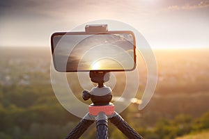 Mobile photography with smartphone on tripod shooting landscape with sunset