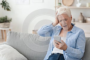 Mobile Scams Concept. Shocked Senior Woman Looking At Smartphone Screen In Frustration