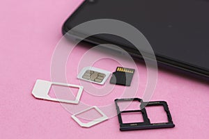 A mobile and SIM and SD memory cards on a pink surface