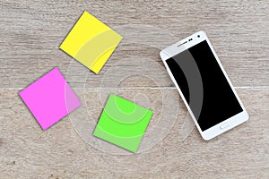 Mobile smart phone with notepad on wood background,