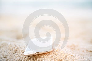 Mobile smart phone put drop on tropical sand beach