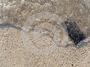 Mobile smart phone on the sandy beach with soft waves of sea background. Insurance concept.