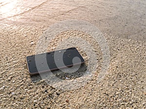 Mobile smart phone on the sandy beach with soft waves of sea background. Internet of thing concept.