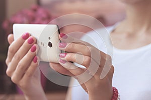 Mobile smart phone in women's hands with a pink manicure on the