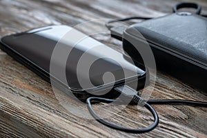 Mobile smart phones charging with energy bank on wooden desk