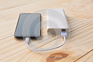 Mobile smart phones charging with power bank on desk and copy sp