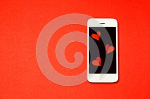 Mobile smartphone with message with grafts on the screen on red background on Valentines Day.