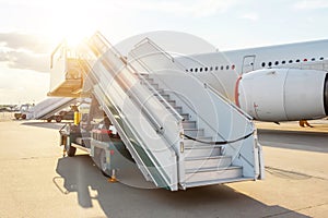 Mobile special equipment with a gangwayladder for boarding and disembarking passengers on the plane at sunset sun