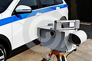 Mobile speed radar on the background of a police car. Traffic safety control of cars on a suburban highway. Close-up