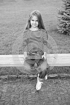 Mobile and tablet internet usage. Little child use tablet sitting on park bench. Mobile personal computer. Cellular