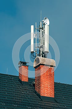 Mobile telephony base station and signal repeater antenna on building roof, telecommunication technology equipment