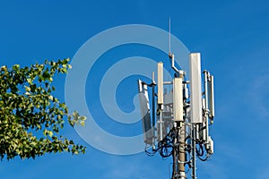 Mobile telephony signal repeater antenna next to a green tree photo
