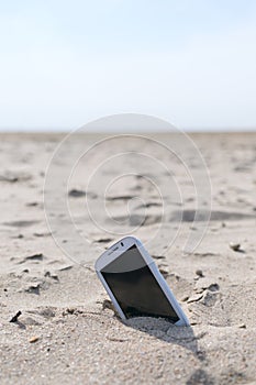 Mobile touch phone in sand on a beach
