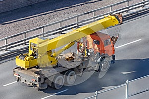 Mobile yellow big crane truck rides on the highway