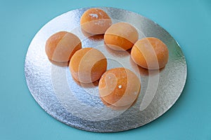 Mochi with mango. Premium ice-cream wrapped in sweet rice dough, traditional japonese desert. Gluten Free. Orange on pastel blue