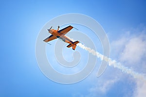 Mochishche airfield, local air show, yellow Extra EX 360 sports plane upside down on blue sky and white clouds background, closeup