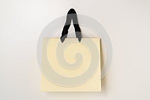 Mock up of beige paper shopping bag with black handles on white background