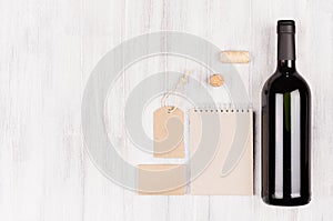 Mock up of blank beige kraft packaging, stationery, merchandise with bottle red wine on soft white wood background, copy space.