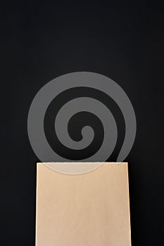 Mock up of blank brown paper shopping bag isolated on black background, copy space, top view, flat lay