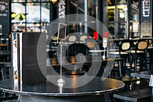 Mock up blank cover menu frame on the blurred background of outdoor coffee and restaurant terrace with tables and chairs