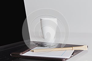 Mock up blank screen laptop and cup of coffee with other office supplies.