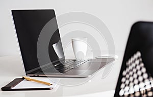 Mock up blank screen laptop and cup of coffee with other office supplies.