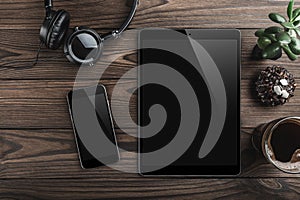 Mock-up blank screen tablet and smartphone, office desk table with headphones, biscuits and coffee cup. Top view