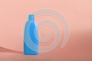 Mock up of a blue bottle with cosmetics product on a pink background. Copy space, pastel colors.