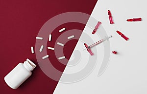 Mock-up bottle with spilled tablets and syringe with ampules filled with red liquid on red and white background