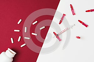 Mock-up bottle with spilled tablets and syringe with ampules filled with red liquid on red and white background