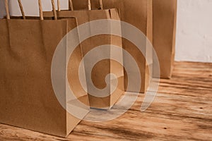 Mock-up of brown craft paper package with handles, empty shopping bag with area for your logo or design, wooden board in